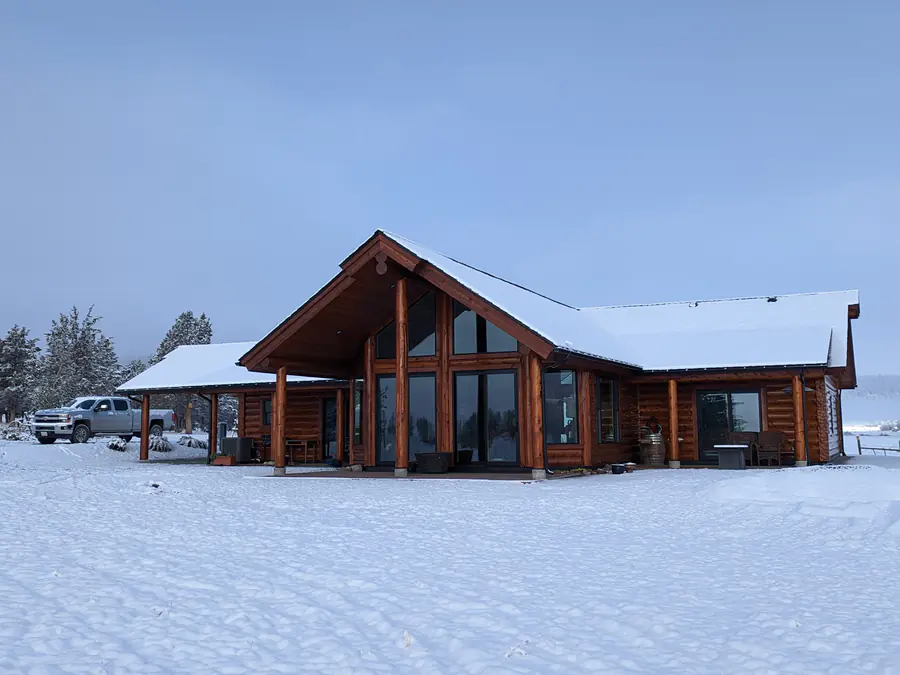 A finished D-log home with a glazed gable end, in fresh snow.