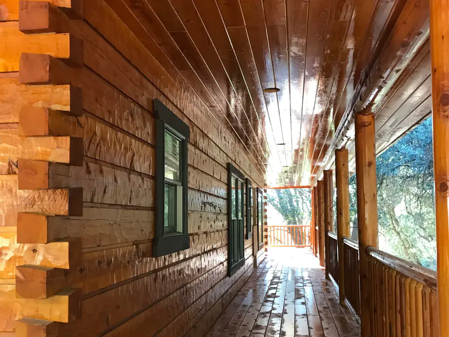 Along a squared timber wall: the dovetail corner in the foreground and the hewn courses running to a covered deck.